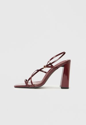Sandale burgundy cu toc înalt, finisaj lucios din lac, cu bretele încrucișate la gleznă și design cu vârf pătrat. Detaliu accent auriu prezent.