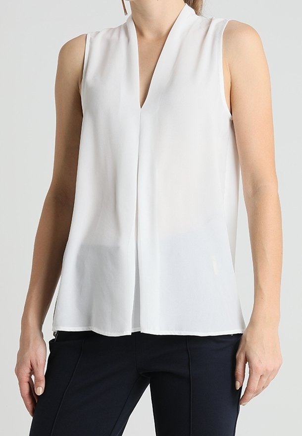 Blusa bianca senza maniche con scollatura a V, realizzata in tessuto leggero, con una vestibilità rilassata e leggermente trasparente.