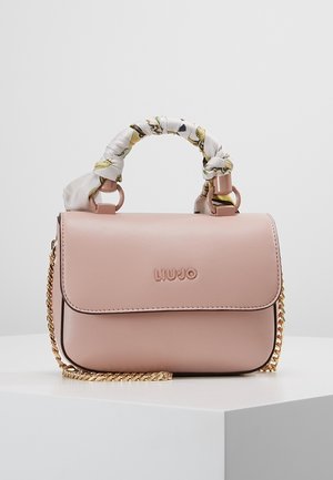 Hellrosa Liu Jo Handtasche mit floral umwickeltem Griff und goldener Kettenriemen, auf einem weißen Podest vor einem schlichten Hintergrund präsentiert.