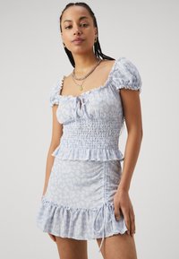 Gaiši zils ziedu raksts kleita ar smockotu krūšu daļu, īsām pufojuma piedurknēm, volānu apakšmalu un sānu saites detaļu.