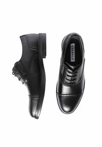 Scarpe eleganti in pelle nera con dettagli brogue, una vista di lato e l'altra vista dall'alto, su uno sfondo bianco.