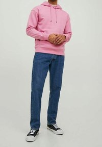 Rosa hoodie med dragkedjor, framficka, i kombination med blå denimjeans och svart-vita sneakers. Enkel design och avslappnad passform.