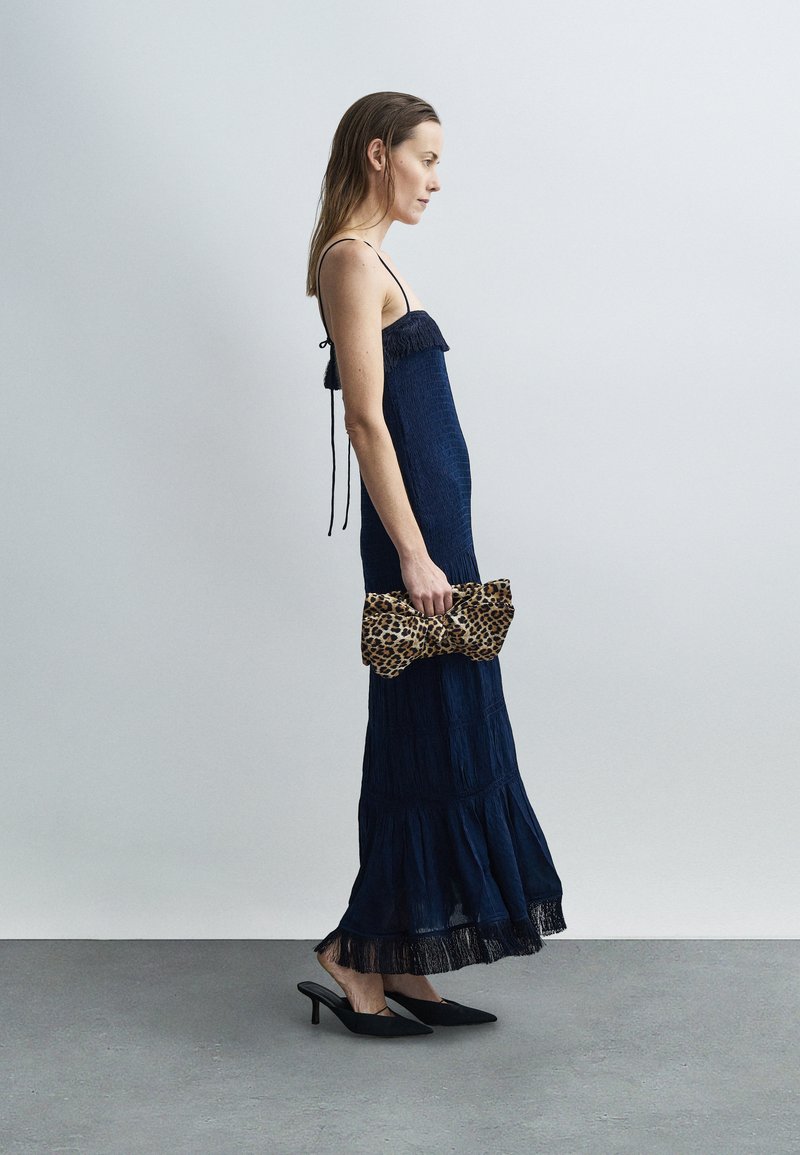 Marineblå maxikjole med frynser og tynde stropper, lagdelt design, stylet med en leopardprint clutch og sorte spidse hæle.