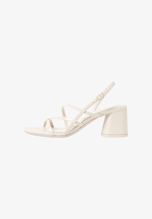 Sandales à talons beiges avec des fines brides entrecroisées, bout ouvert et un talon carré. Fini en vernis lisse, bride de cheville réglable.