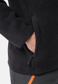 Zwarte fleecejack met een ritszak. Kenmerkt zich door een gestructureerd oppervlak, strakke manchetten en een slank ontwerp, geschikt voor casual kleding.