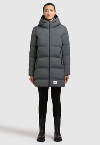 Manteau doudoune gris avec capuche, doté d'une fermeture éclair à l'avant, de deux poches latérales et d'une patch logo blanc à l'ourlet. Texture lisse et rembourrée.