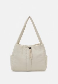 Smėlio spalvos dygsniuota peties rankinė su apvalia forma, reguliuojamu raišteliniu uždarymu ir dviem šoninėmis kišenėmis. Minkšta medžiaga ir elegantiškos rankenos.