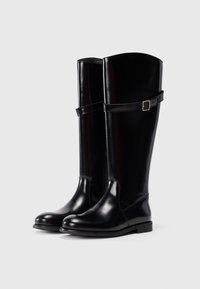 Pair of tall black leather boots with rounded toes and ankle straps featuring small square buckles, shown on a plain background.