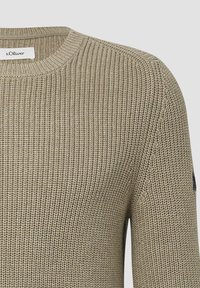 Khakifarbenes, geripptes Strickpullover mit Rundhalsausschnitt, der ein schwarzes Logo-Detail am linken Ärmel aufweist. Strukturierter Stoff, mittelschweres Design.