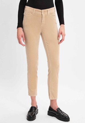 Beige Corduroyhosen mit slim Fit, ausgestattet mit einem klassischen Five-Pocket-Design und einem Knopfverschluss. Getragen mit schwarzen Plateauschuhen.