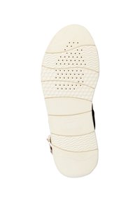 Suela de goma crema con agarre texturizado, que presenta un patrón de surcos y perforaciones. Logo de la marca visible en la suela.