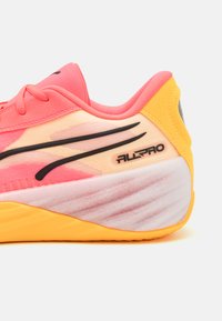 Lette basketballsko i pink og gul med en struktureret overflade, sorte strømlinede accenter og en polstret krave for komfort.