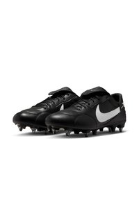 Fekete focicipők letisztult dizájnnal, szintetikus bőr anyagból, fehér Nike logóval, fűzős záródással és öt látható cleattal minden talpon.