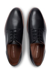 Μαύρα δερμάτινα παπούτσια με λείο φινίρισμα, σχέδιο με κορδόνια και καφέ λαστιχένιες σόλες. Το λογότυπο είναι ορατό στις εσωτερικές σόλες.