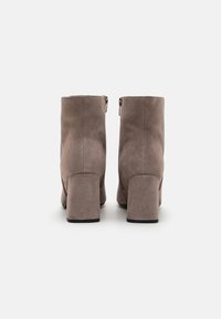 Hnědé kotníkové boty z broušené kůže s blokovým podpatkem, zadním zipem, hladkou texturou a klasickým designem. Podpatky mají přibližně 4 cm na výšku.