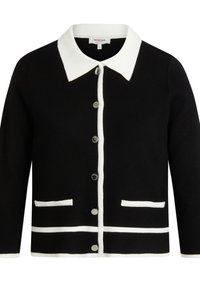Zwarte cardigan met een witte kraag, voorzien van een witte bies, twee voorzakken en zes zilveren knopen in het midden.