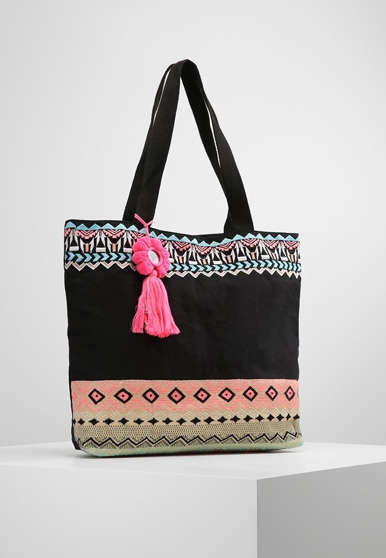Bolso tote negro con bordado decorativo que presenta patrones en rosa, azul y verde. Incluye un borlas rosa y asas negras resistentes.