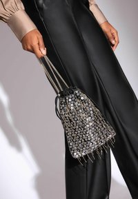 Fekete húzózsinóros tasak, flitteres anyagból készült, ezüst lánc vállpántokkal és dekoratív rojtokkal. Simás textúra fényvisszaverő részletekkel.