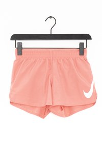 Nike sportshorts i ljusrosa, tillverkade av ett mjukt tyg, har en elastisk midja och en stor vit swoosh-logga på sidan.