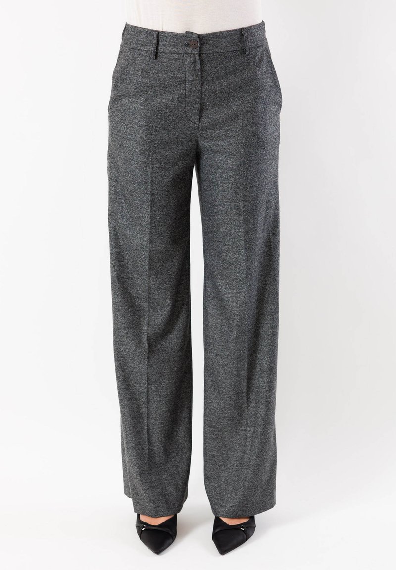 Pantaloni grigi a gamba larga con tessuto strutturato, tasche frontali e chiusura con bottone, abbinati a scarpe nere con punta.