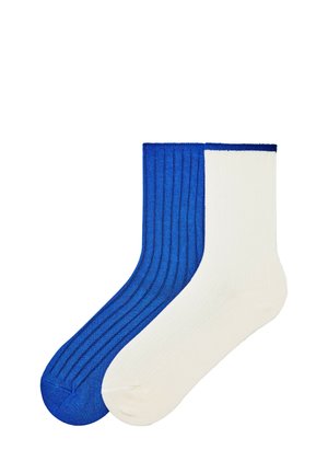 Deux chaussettes côtelées hauteur cheville, une bleue unie et une blanche unie, posées côte à côte sur un fond blanc.