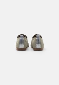 Zapatos de ante gris con un acento azul claro en el talón, borde festoneado y una suela de madera marrón. Presentan un diseño de punta redondeada.