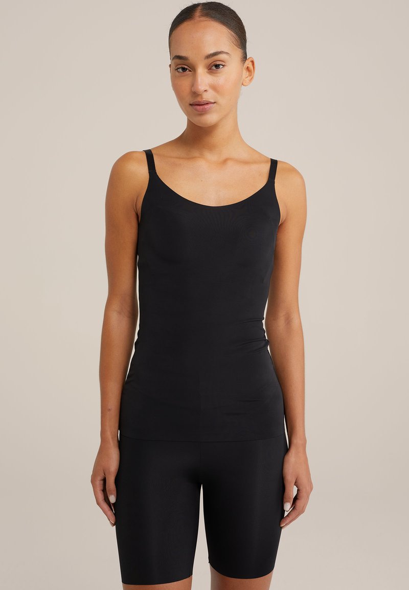 Črna majica brez rokavov s tankimi naramnicami, izdelana iz gladkega, raztegljivega materiala. V kombinaciji z ujemajočimi se črnimi kolesarskimi kratkimi hlačami, ki imajo prilegajoč dizajn.