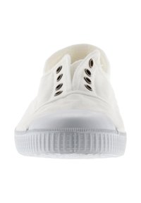 Zapatilla slip-on de lona blanca con seis ojales metálicos vacíos y suela de goma blanca texturizada, vista desde el frente.