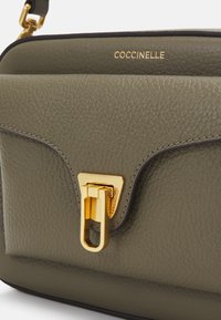 Borsa a tracolla in pelle verde oliva con superficie texturizzata, hardware dorato e chiusura triangolare. Presenta il nome del marchio impresso in oro.