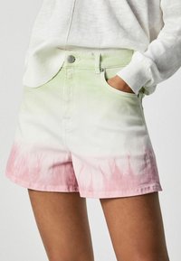 Shorts de mezclilla con un diseño degradado en verde claro en la parte superior que se desvanece a rosa en el dobladillo, con un corte holgado y bolsillos estándar.