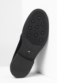 Suola di scarpa in gomma nera con motivi di battistrada circolari, caratterizzata da un logo in rilievo "NeroGiardini" e da un marchio "Made in Italy" con i colori della bandiera italiana.