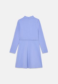 Robe à manches longues de couleur bleu clair avec un dos en trou de serrure et une taille ajustée. Présente un logo sur la ceinture et une texture lisse.