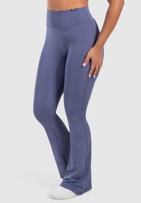 Hoch taillierte, austellende Leggings in einem einfarbigen tiefblauen Farbton, hergestellt aus einem glatten, dehnbaren Material mit kontrastierenden Nahtdetails und einem Logoetikett.