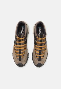 Des chaussures de sport avec une tige en daim brun, des accents noirs et des lacets multicolores. Semelle en caoutchouc noir texturé avec de profondes rainures.