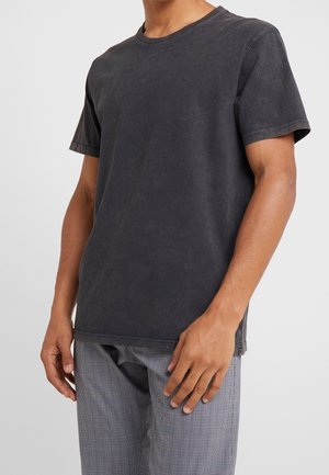 Czarny bawełniany T-shirt z okrągłym dekoltem, krótkimi rękawami i lekko zużytą teksturą. Fason casualowy, w połączeniu z wzorzystymi spodniami.