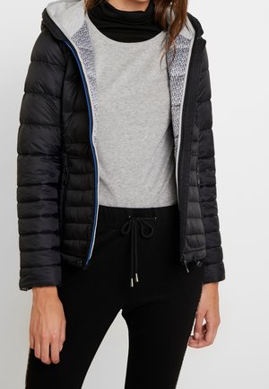 Zwarte pufferjack met een grijze binnenkant en blauwe accenten op de ritssluiting, gedragen over een grijze top en zwarte broek met een trekkoord.