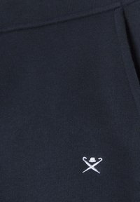 Marineblauwe sweatshirts met een zachte textuur, voorzien van een geborduurd wit logo van kruislings geplaatste stokken en een hoed op het linkerbovenbeen.