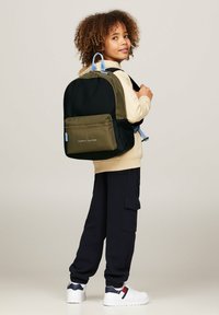 Zaino nero e verde oliva con una tasca frontale con zip e dettagli azzurri chiari, realizzato in materiale resistente e dotato di spallacci imbottiti.