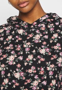 Sweat à capuche noir avec un motif floral présentant des roses roses et rouges. Design à capuche avec texture douce et détails subtils.