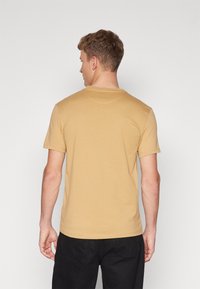 Kortærmet T-shirt med rund hals i sennepsgul bomuld, med en glat overflade og lige kant, set fra ryggen.