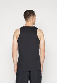 Canotta nera in cotone, con scollo rotondo e design senza maniche, caratterizzata da un taglio semplice e pulito, senza motivi visibili.