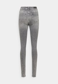 Calças skinny em denim cinza médio. Apresentam uma cintura alta, cinco bolsos e uma textura suave. Design minimalista sem adornos visíveis.