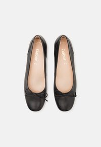 Zwarte leren balletschoenen met een ronde neus, gladde textuur en decoratieve strikdetails aan de voorkant. Lichtgekleurde binnenzool met merknaam.