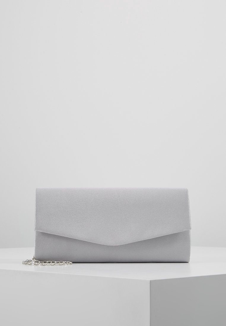 Pochette rectangulaire grise avec fermeture à rabat et bandoulière en chaîne argentée reposant sur une surface blanche.