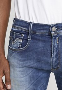 Jeans i denim med en blekt mörkblå färg, med fem fickor, detaljerad sömnad och en silverknapp framtill.