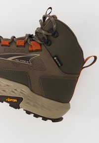 Brune tursko med teksturert overdel, oransje detaljer, Gore-Tex-merke og Vibram såle med karakteristisk grep mønster.