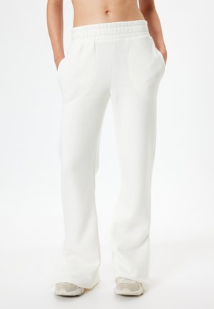Witte, wijde sweatpants met een textuurafwerking, een elastische tailleband en diepe zijzakken, gecombineerd met lichte sneakers.