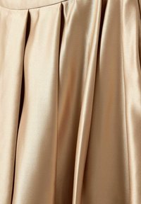 Tissu soyeux beige avec des plis lisses créant des reflets de lumière doux et des plis délicats.