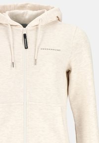 Light beige zip-up hoodie made from soft fabric. Features a drawstring hood, front pockets, and “SWEDEMOUNT” logo in gray.