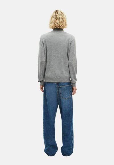 Grijze langslaf t-shirt met hoge hals, gecombineerd met losse blauwe denim jeans met een achterzak. Gladde textuur en ontspannen pasvorm.